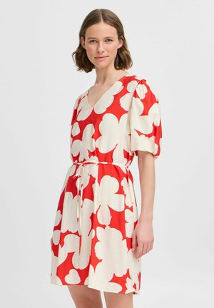 Red and white floral dress with puff sleeves, V-neckline, and a tie waist. The fabric has a smooth texture with a bold, large flower pattern.