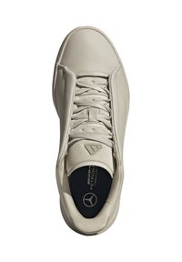 Beige läder sneakers med rund tå, texturerade detaljer, platta snören och logotyp på tungan. Har vadderad sula och slät ytstruktur.