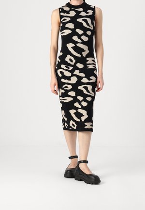 Czarna sukienka midi bez rękawów z beżowym abstrakcyjnym zwierzęcym wzorem, noszona z czarnymi masywnymi butami na kostkę z paskiem.