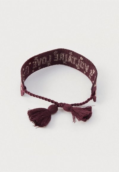 Braccialetto lavorato a maglia bordeaux con nappine e dettagli testuali. Presenta un design intrecciato e una texture morbida, adatto per un look casual.