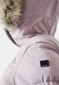 Světlofialová péřovka s kapucí lemovanou kožešinou, na rameni s černým logem a hladkým, matným povrchem.