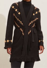 Black knitted robe with floral embroidery in orange and yellow, fringed edges, long sleeves, and a tied waist belt. Two front pockets.