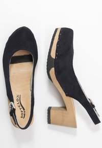 Marina mocka klackar med rund tå och öppen baksida. Träblockklack och ljust brun innersula, med kontrasterande sömmar och hårdvara.