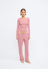 Κόκκινο και λευκό ριγέ μακρυμάνικο τοπ και αντίστοιχο παντελόνι, κατασκευασμένα από μαλακό ύφασμα, με εφαρμοστή γραμμή και ελαστική μέση με κορδόνι.