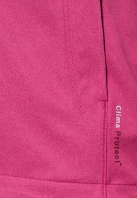 Tissu rose vif avec coutures visibles et étiquette imprimée portant la mention "Clima Protect" en bas à droite.