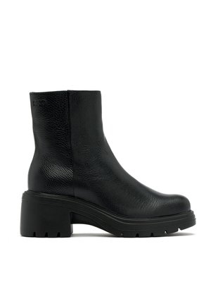 Bottines noires en cuir avec une finition texturée, talon bloc et semelle robuste ; elles présentent un bout lisse et un détail de logo subtil sur le côté.