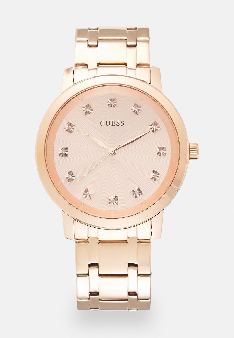 Montre en or rose avec un bracelet métallique, un cadran rose clair texturé et des marqueurs en cristal à chaque heure, affichant un design minimaliste.