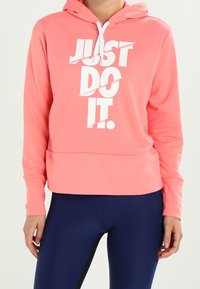 Roze hoodie gemaakt van zachte stof, met een witte "JUST DO IT" opdruk. Het ontwerp heeft een relaxte pasvorm en een kangoeroezak.