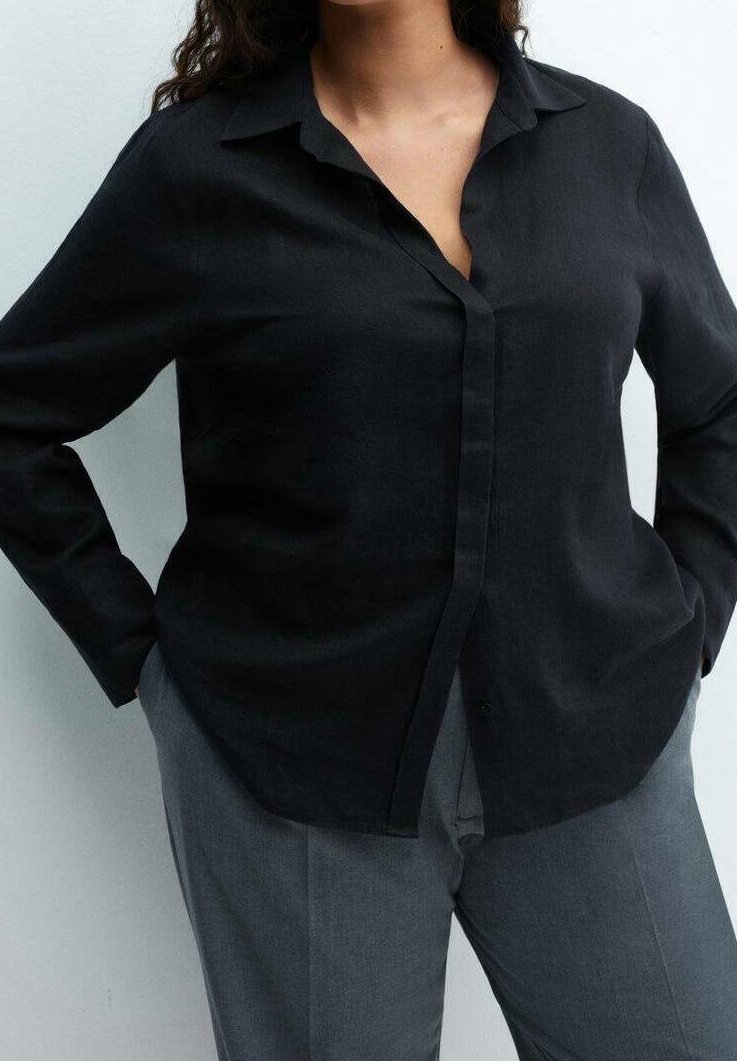 Chemise noire boutonnée en tissu doux avec un col, une patte de boutonnage sur le devant et des manches longues, associée à un pantalon gris. Design simple et classique.