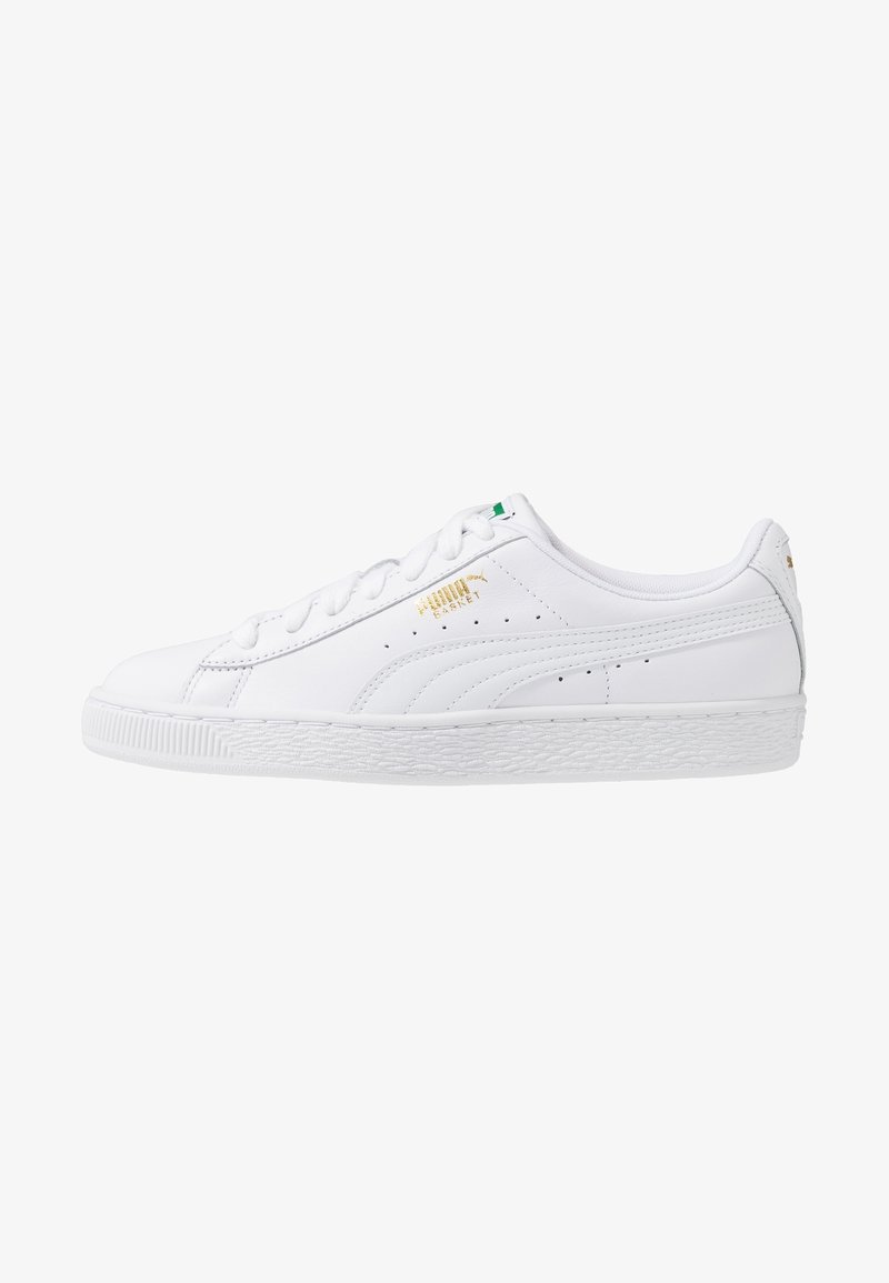 White leather sneakers with a textured white rubber sole, featuring gold branding, a green accent on the tongue, and perforated detailing.