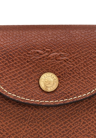 Brown textured leather wallet with a gold circular logo, featuring a detailed embossed pattern and contrast stitching along the edges.