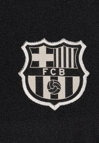 FC Barcelona logo in black and white, featuring a shield design with vertical stripes, a cross, and a stylized soccer ball at the bottom.