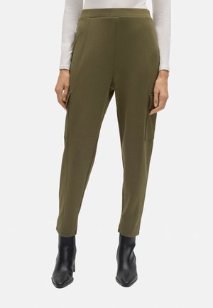 Pantalones verde oliva hechos de una tela suave, con cintura alta, bolsillos laterales y un diseño de pierna ajustada. Llevados con botines negros.
