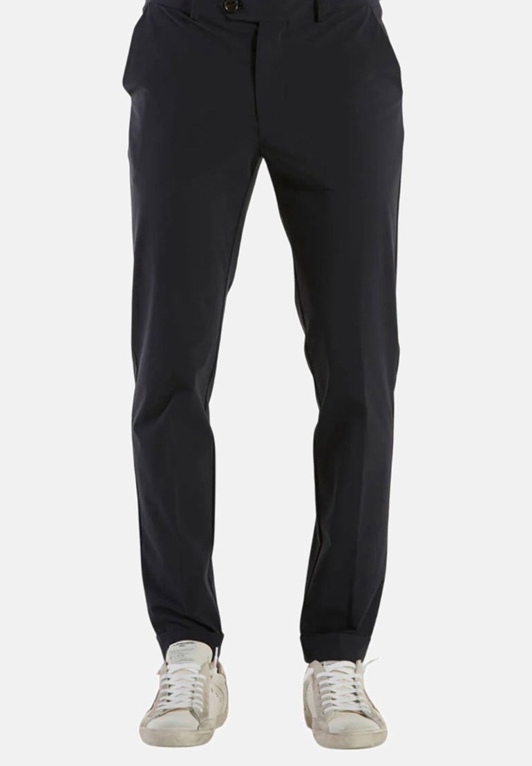 Pantaloni su misura blu navy con una texture liscia, una vestibilità slim, tasche frontali e chiusura a bottone, abbinati a sneaker bianche.