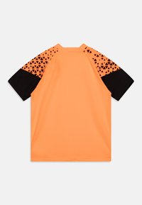 Maglia a maniche corte di colore arancione con dettagli neri, caratterizzata da un motivo geometrico sulle spalle. Realizzata in un tessuto leggero e liscio.