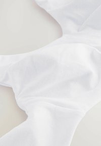 Tejido blanco, textura suave, material flexible, presenta un diseño recogido con suaves pliegues. No hay hardware ni patrones visibles.