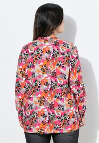 Camicia a maniche lunghe con un motivo astratto colorato caratterizzato da accenti rosa, arancio, grigio e nero. Realizzata in un tessuto leggero.
