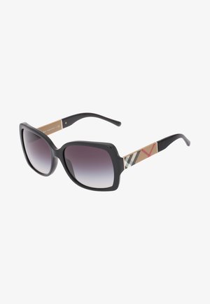 Ochelari de soare negri, supradimensionați, cu lentile degradate. Bratele au un design bej cu un model în carouri și accente roșii.