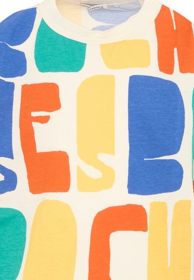 Tissu crème avec de grandes lettres majuscules colorées en orange, bleu, jaune et vert formant un motif audacieux et abstrait.