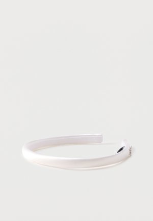 Hvid polstret satin hovedbånd med små rhinestone accenter i den ene ende, sat mod en ensfarvet lys baggrund.