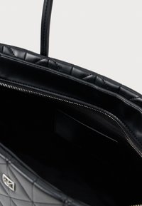 Čierna prešívaná kožená taška s hladkým, lesklým povrchom. Vnútri sa nachádza vrecko na zips a látková podšívka. Dodávaná s pevným držadlom.