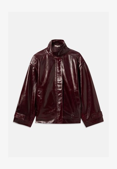 Spīdīga tumši burgundijas krāsas ādas jaka ar augstu apkakli, priekšējo spiedpogu aizdari, sānu kabatām un regulējamiem spiedpogām pie piedurknēm.