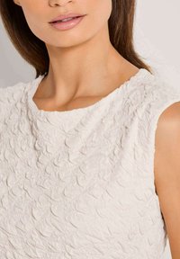 Texturiertes weißes ärmelloses Top mit einem weichen, erhöhten Muster. Rundhalsausschnitt und glattes Material sorgen für ein leichtes, luftiges Erscheinungsbild.