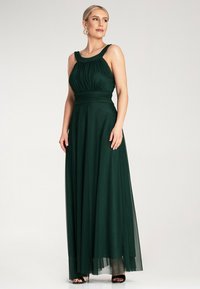 Długa, ciemnozielona sukienka wykonana z płynnego materiału, z marszczoną górą, szerokimi ramiączkami i zwężoną talią, z warstwową spódnicą.