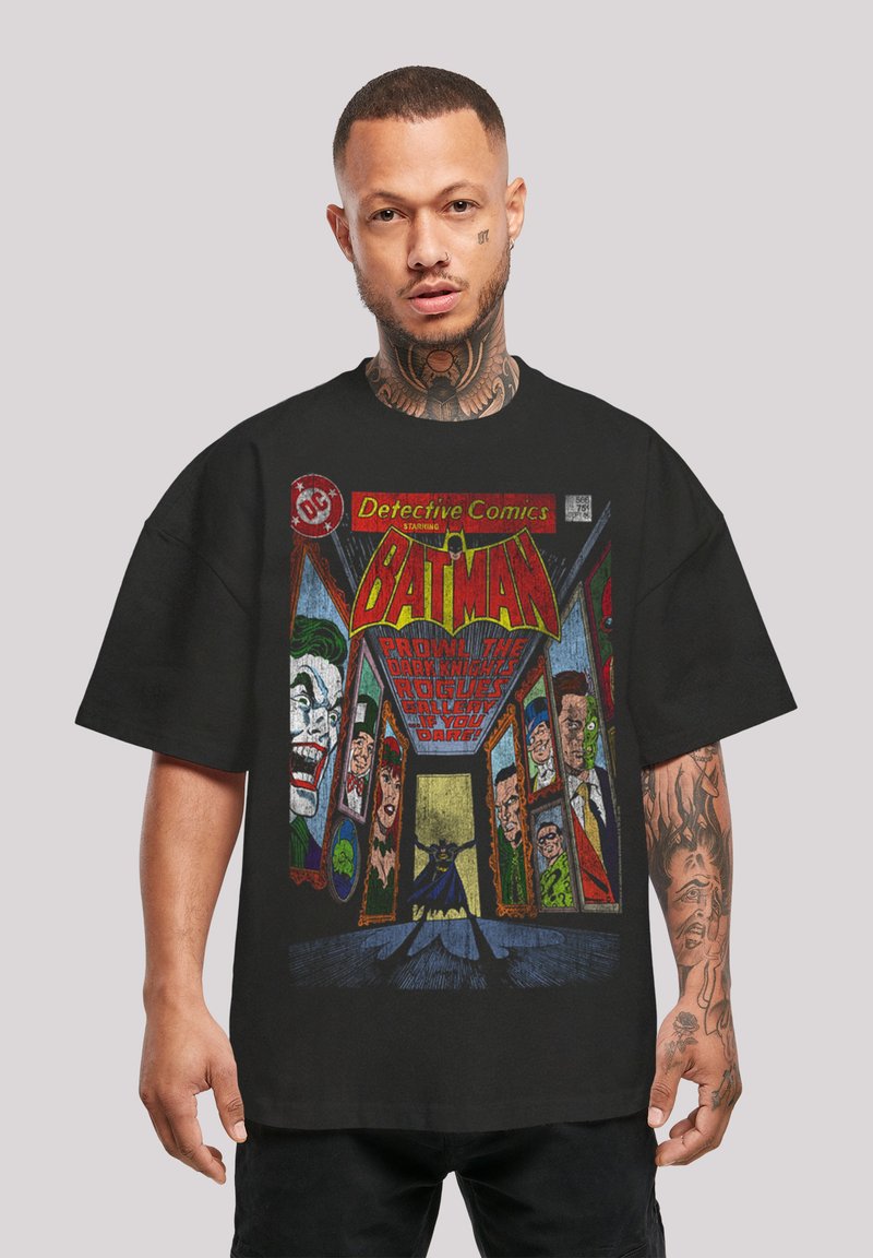 Camiseta negra de gran tamaño con un diseño de cómic que presenta a Batman y villanos, gráficos coloridos y texto de estilo vintage.