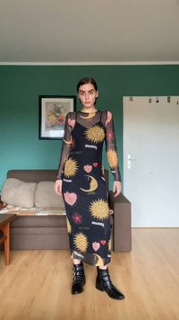 Musta pitkähihainen mekko, jossa on auringon ja sydämen grafiikoita, sopivalla siluetilla ja läpinäkyvällä verkkokankaalla. Yhdistettynä mustiin niiteillä varustettuihin nilkkabootseihin.