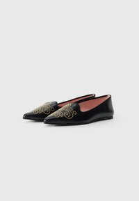 Ballerines en cuir noir à bout pointu, ornées de motifs en spirale cloutés dorés sur le dessus et d'un intérieur lisse et contrasté.