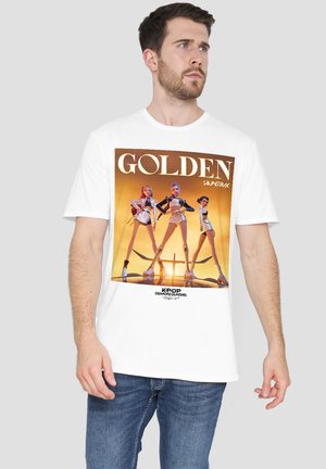 Man wearing white T-shirt with graphic of three futuristic female K-pop characters posing against a golden background.