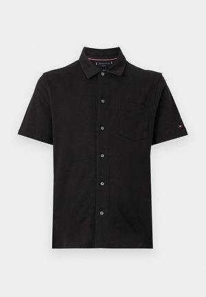 Polo noir à manches courtes avec col, doté d'une fermeture à bouton et d'une poche poitrine. Fabriqué en tissu texturé avec des accents subtils.