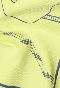 Gul stof med en struktureret overflade, der viser et marineblåt geometrisk mønster og prikker, hvilket skaber en subtil visuel kontrast.