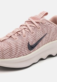 Lys rosa Nike joggesko med teksturert overdel, tonale striper, svart swoosh-logo og hvit yttersåle. Har rund tå og snøring.