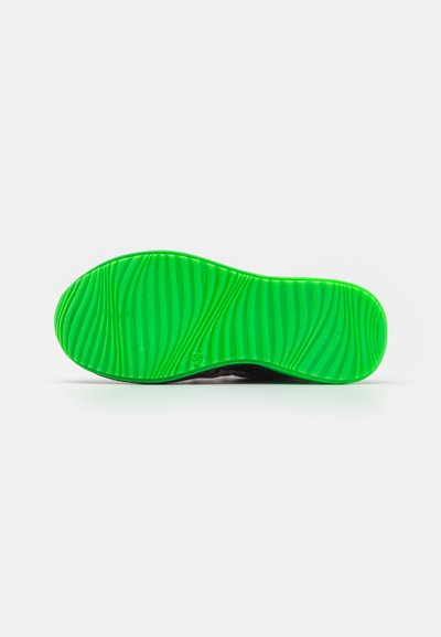 Shoe sole in vibrant green rubber with textured wavy patterns, featuring a black edge. The design appears lightweight and flexible.