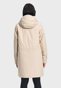 Svijetlosmeđi zimski park s kapuljačom, dugim rukavima i blago suženim strukom. Glatka tekstura s minimalnim detaljima. Prikazan stražnji pogled.