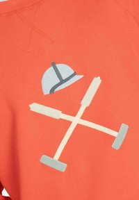 Sudadera naranja con un casco azul y herramientas beige en un patrón cruzado, con detalles bordados y una textura de tela suave.