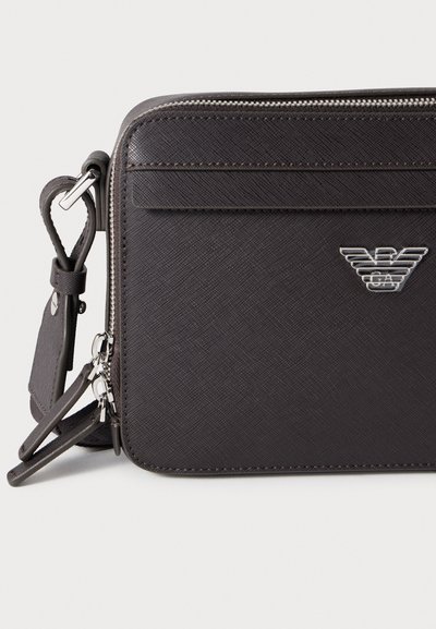 Μαύρο υφασμάτινο τσάντα ώμου με υφή, με ασημένιο λογότυπο, κλείσιμο με φερμουάρ και ρυθμιζόμενο ιμάντα. Διαθέτει μπροστινή τσέπη και μεταλλικές λεπτομέρειες.