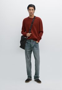 Röd stickad tröja, ljusblå jeans, mörk axelväska. Mjukt material, avslappnad passform, enkelhet i designen, med kontrasterande färger och material.