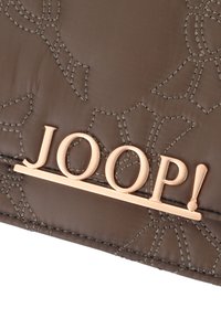 Rjava prešita tkanina z dvignjenim cvetličnim šivanjem in poudarkom v rožnato zlatem "JOOP!" logotipu. Gladka tekstura z rahlim sijajem.