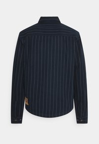 Navy striped shirt with long sleeves, button cuffs, and a pointed collar; features light blue vertical stripes and a brown label on the hem.
