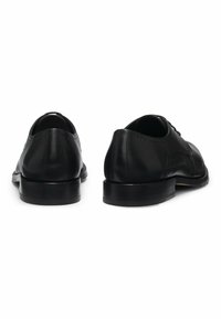 Scarpe eleganti in pelle nera con una superficie liscia, punta arrotondata, design con lacci e suola piatta in gomma che presenta dettagli minimalisti.