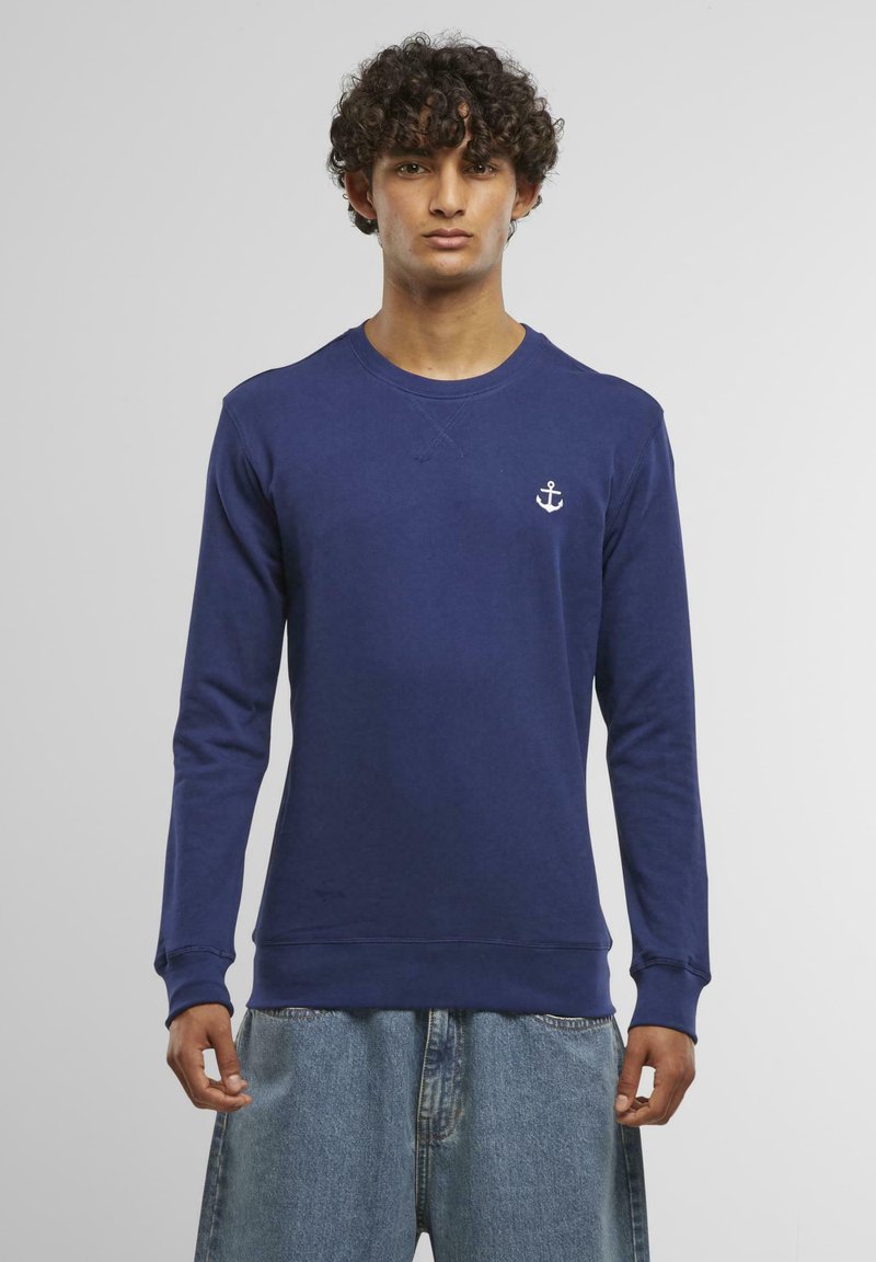 Navy blue sweatshirt with long sleeves, crew neck, and white anchor logo on the chest. Made from soft fabric with ribbed cuffs and hem.