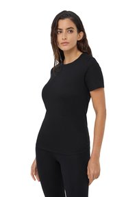 Czarny t-shirt z krótkim rękawem wykonany z miękkiego materiału, z okrągłym dekoltem i dopasowanym krojem, noszony z czarnymi legginsami.