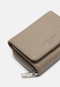 Billetera de cuero taupe compacta con solapa y tirador de cremallera plateado, embellecida con el logo "Liebeskind Berlin" en la parte frontal.