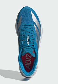 Sinine sünteetiline spordijalgpadi hõbedaste aktsentide, tekstureeritud ülemise osa, lamede paelte ja punase sisemusega, millel on "ADIZERO" bränding keeles.