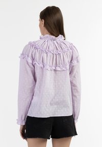 Lila blouse met gerimpelde accenten, gestructureerde stof met verhoogde stippen, gathered halslijn en lange mouwen met elastische manchetten.