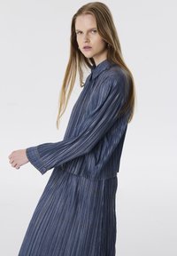 Blauw, gestreept, langemouwen shirt met een kraag, met licht stikwerk en een ontspannen pasvorm. De stof lijkt licht en textuur te hebben.