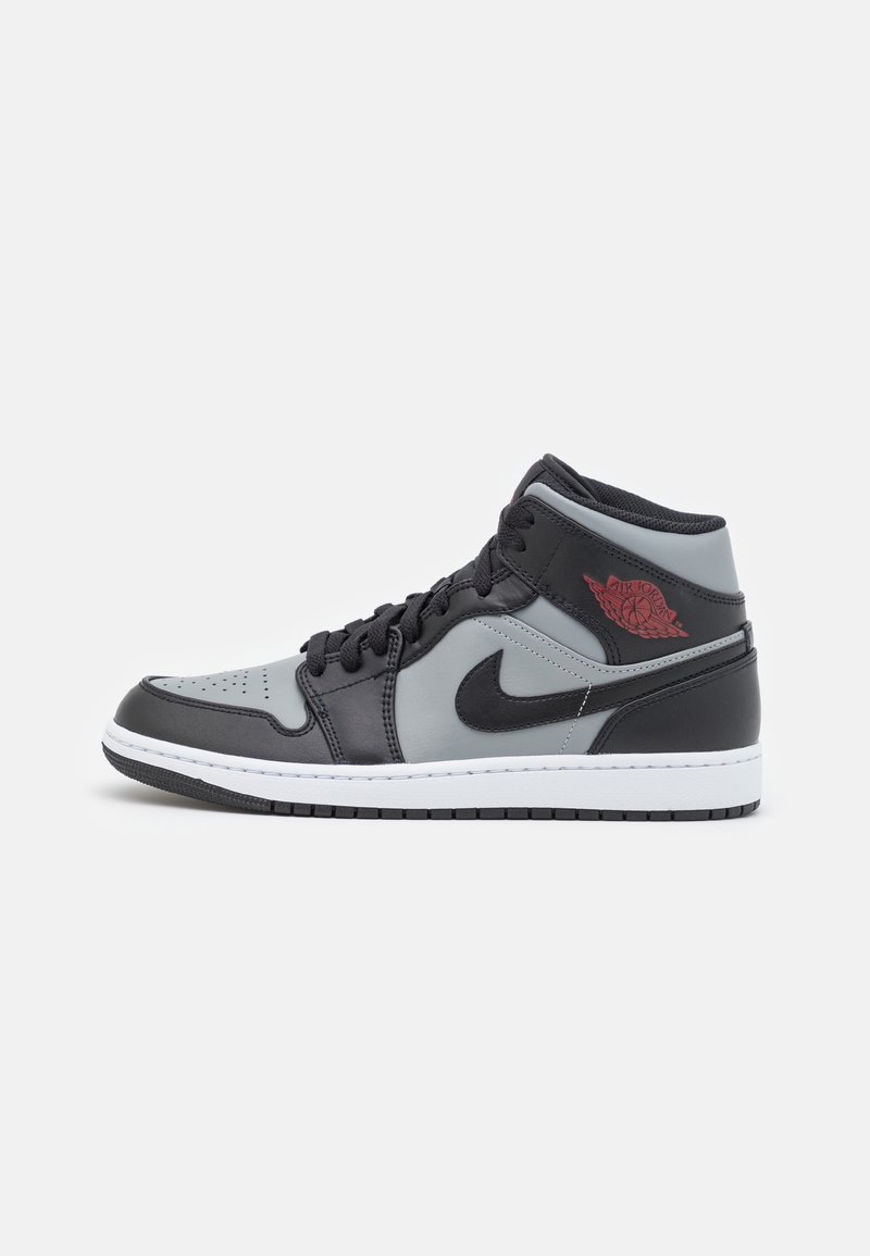 Baskets montantes Nike Air Jordan noir et gris avec logo rouge, virgule noire, semelle intermédiaire blanche et semelle extérieure noire sur fond blanc.